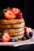 Pile of English crumpets with berries and honey, close-up