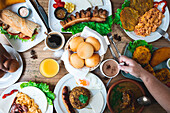 Top view of unrecognisable woman drinking cocoa and eating various delicious Latin American dishes while having lunch in a restaurant