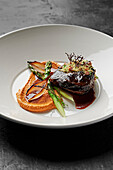 Slow-cooked beef cheek, charred shallots, asparagus spears, romesco, pancetta herb crumbs