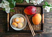 Japanische Mango-Mochi-Törtchen mit Eiscreme auf einem klassischen asiatischen Holztablett