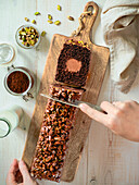 Travel Cake or Tube Cake or Voyage Cake, filled with ganache in the centre and topped with chocolate icing and pistachios (can also be made with peanuts). Chocolate cake with chocolate cream cheese filling in the centre. Idea and recipe for baking with ganache cream centre. Loaf cake on women's hands