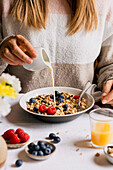 Milch in einer Schüssel mit Müsli, frischen Beeren und Orangensaft