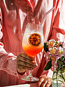 Aperol Spritz cocktail, on a pale pink linen tablecloth, shade, sunlight, summer drink in a glass