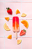 Fruit popsicle with ingredients over pink tile background