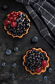 Pastries basket with blueberries and raspberries. Cake on a dark background. Top veiw.