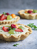 Fresh fruit and custard cream tart decorated with mint leaves