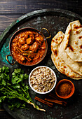 Chicken tikka masala spicy curry meat food with rice and naan bread on dark background