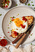Chilli cheese on toast, topped with a fried egg whose yolk is broken