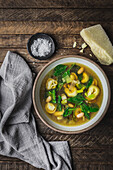 Tortellini, spinach and broth in a bowl with parmesan cheese and napkin_wide
