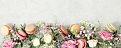Spring flowers and Different types of macaroons background top view, banner size, flat lay
