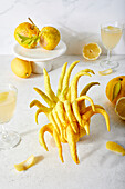 Tablescape with Buddha's hand lemon, yuzu, lemons and citrus drinks on white background