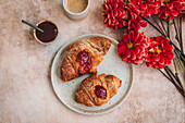 Croissants with strawberry jam on a ceramic plate