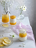 Lemon curd and greek yogurt with thyme in glass jars. Soft romantic scene.