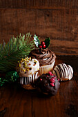 Weihnachtlicher Schokoladen-Cupcake und Profiteroles vor einem dunklen Holzhintergrund, mit Kopierbereich
