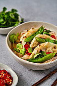Veggie Gyoza Noodles with Sugar Snap Peas, Corainder and Chilli on grey surface