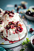 Meringues mit frischer Sahne und reifen Kirschen auf blauem Hintergrund