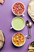 Three poppadom dips: mint yoghurt sauce, red onion chutney, mango chutney, served with poppadoms