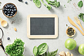 Vegetarian vegan healthy ingredients and blank chalkboard on grey stone background. Healthy food, eco-friendly, zero waste concept
