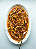 Chicken feet in oval dish on marble background