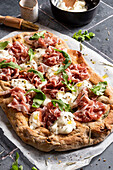 Pizza with prosciutto, arugula, cheese and olive oil