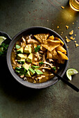 Green chicken chili soup in a bowl garnished with avocado, cilantro, tortillas, and cotija cheese.