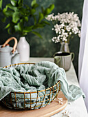 Empty wire bread basket with cloth on a cutting board next to the window