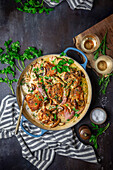 Chicken in wine cream sauce with mushrooms, shallots and parsley in a blue enamelled pot with spoon and napkin