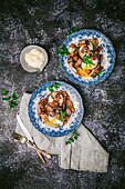 Two pretty antique plates with runny poached eggs, shallots, mushrooms and bacon in red wine sauce, on dark background