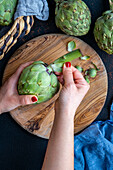 Women's hands removing the outer leaves of an artichoke