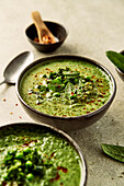 Pea, mint and kale soup on a light green background with chilli