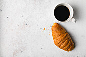 Tasse Kaffee und Croissant über Tisch