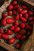 Wooden crate full of fresh strawberries on a wooden table