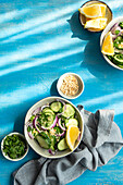 From above of healthy vegetables salads with organic cucumber, red onion, coriander and chopped nuts placed in a blue concrete table