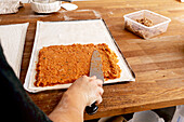 Top view of anonymous mature baker dressed in casuals putting pastry delicious stuffing on dough at table while working in bakery kitchen