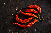 Top view of dried red hot criollo long Ecuadorian peppers placed on black table