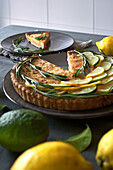 From above of round lemon pie with decorated with lemon slices and rosemary sprigs on table with a grey towel