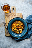 Top view of a chicken meat stew with vegetables served in the ceramic bowl and glass of amber wine