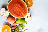 Top view of crop seasonal fruit frame consisting of watermelon, orange, pear, grapes and apples placed on white surface