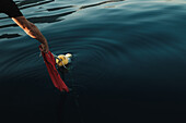 Körperteil eines männlichen Seemanns, der ein Netz mit einer aufblasbaren Boje beim traditionellen Fischfang im offenen Meer in Soller nahe der Baleareninsel Mallorca aufstellt