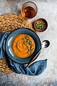 Tasty pumpkin cream soup with organic herbs and seeds in blue vintage ceramic bowl