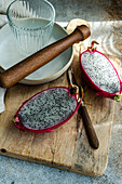 Sliced dragonfruit on a rustic wooden board with a rolling pin and ceramic plates.