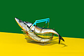 Side view of fish in metal basket placed on yellow table against green wall