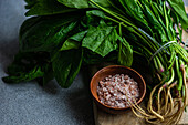 Frischer Blattspinat gepaart mit aromatischen Gewürzen in einer Holzschale vor rustikalem Hintergrund, ideal für einen gesunden Gemüsesalat