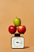 Fresh and juicy red and green apples on weighing scale as part of healthy calorie controlled diet on colored background
