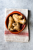 Red ceramic bowl with ginger roots on rustic towel on concrete table