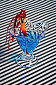 High angle of blue cocktail glass garnished slice straw while served on stripes cloth surface