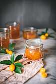 Glass jar with fresh kumquat jam on table over blur dark grey background