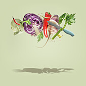 Kreative Lebensmittel Levitation Konzept mit fliegenden verschiedenen bunten Gemüse und Messer auf blassem grünen Hintergrund. Gesunder Lebensstil