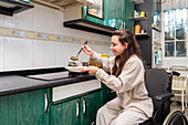 A smiling young woman in a wheelchair serves herself a healthy meal, showcasing independent living