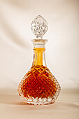 Decanter fill with whiskey placed on table against white background in daylight